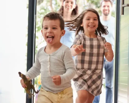 Kids excitedly running into house with parents happily walking behind